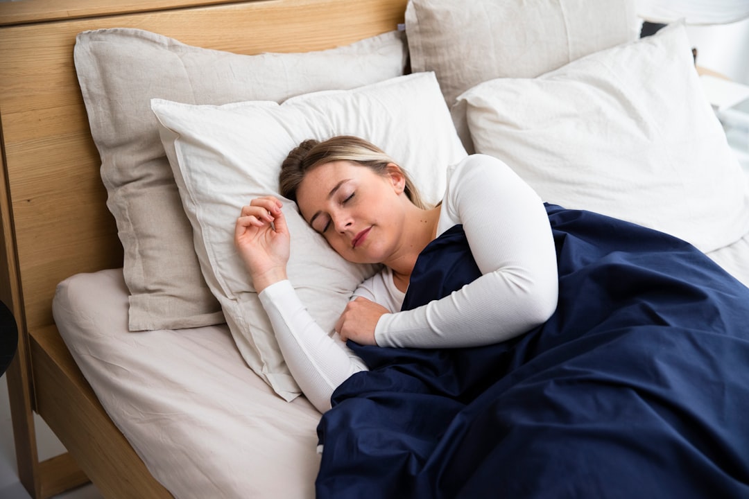 une-femme-dormant-sur-un-lit-avec-une-couverture-bleue-6qxUg4jTWdE